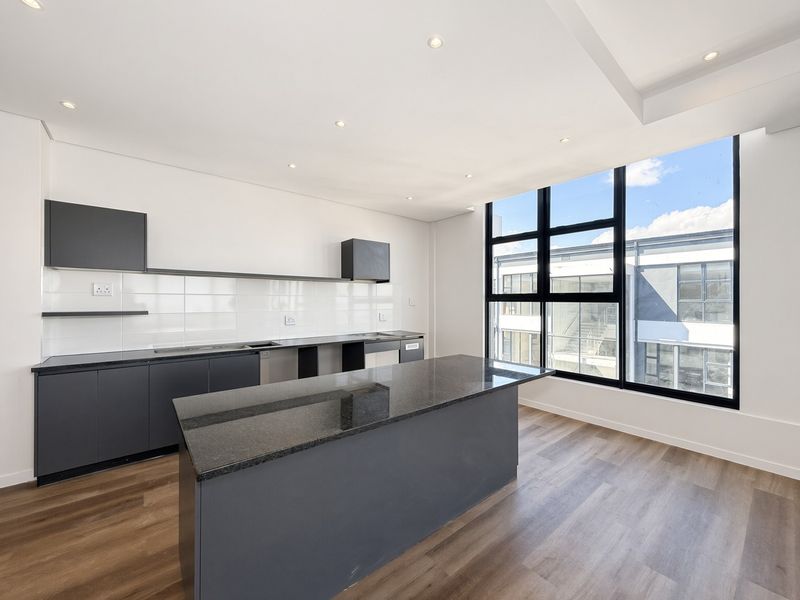Modern kitchen featuring a central island, dark cabinetry, granite countertops, and large windows providing ample natural light.