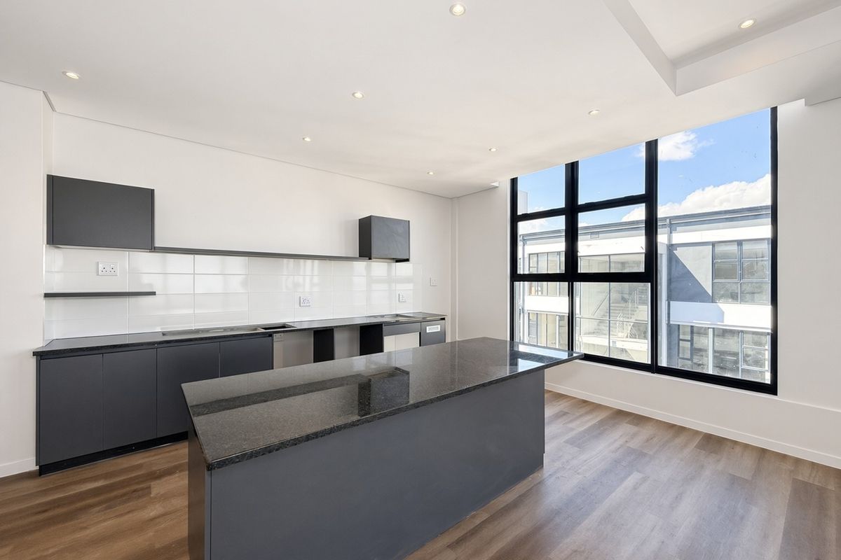 Modern kitchen featuring a central island, dark cabinetry, granite countertops, and large windows providing ample natural light.