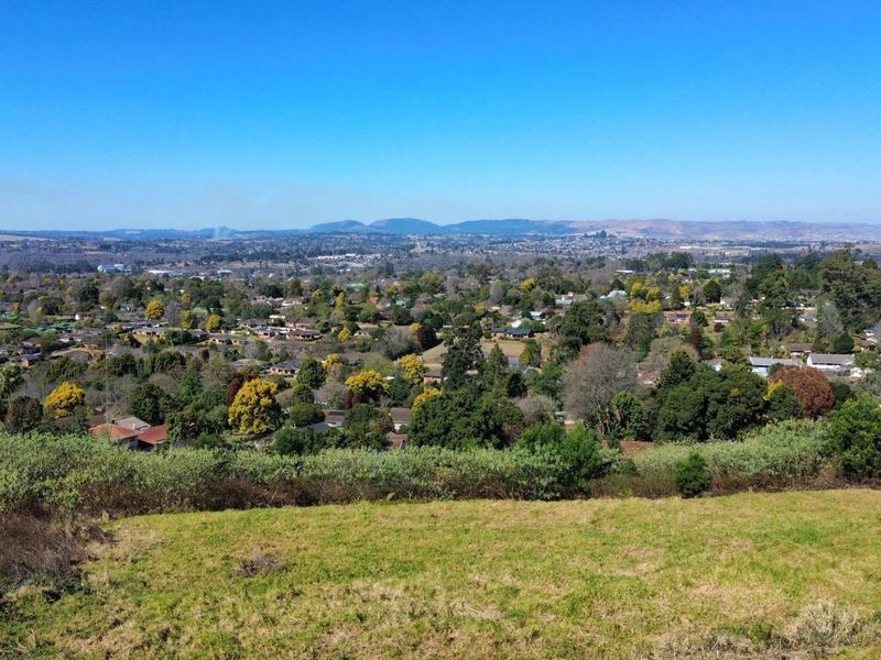 An elevated panoramic view overlooking a residential neighborhood and surrounding landscape from the vacant land plot.