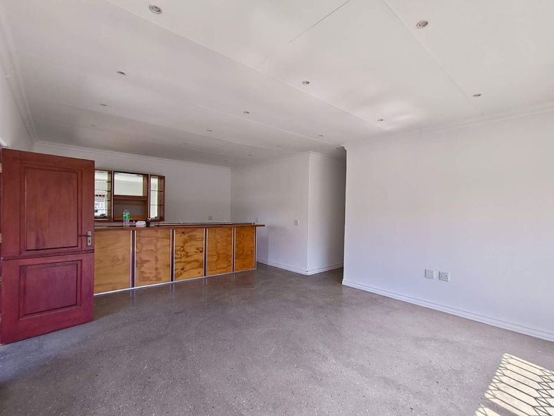 An open-plan living area featuring polished concrete floors, recessed lighting, and a built-in timber bar counter.