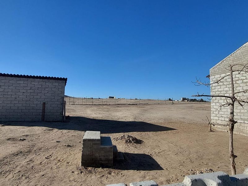 Rear view of the small holding property featuring unfinished masonry structures and expansive undeveloped land.