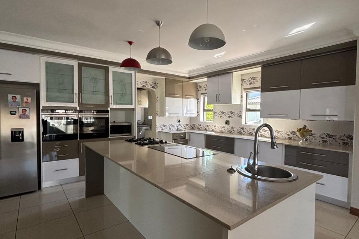 Modern kitchen featuring a large central island with stone countertops, built-in appliances, ample cabinetry, and tiled flooring.
