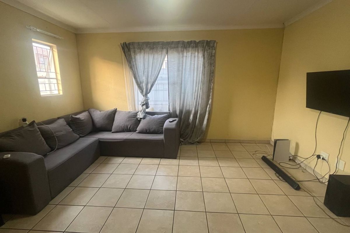 A living room featuring tiled flooring, coving, and security bars on the window, providing a functional space with potential for cosmetic updates.