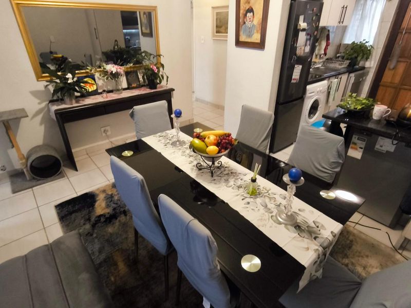 Open-plan dining area seamlessly connected to a functional kitchen space with tiled flooring and built-in cabinetry.