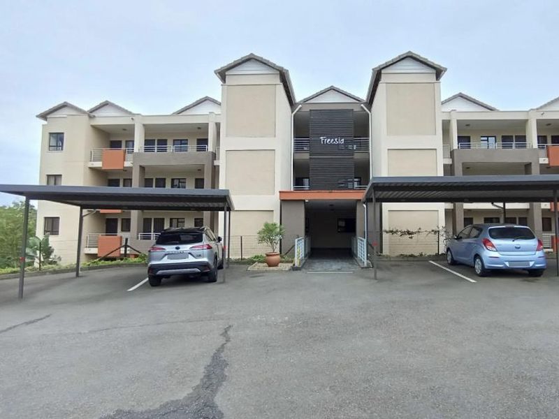 Front elevation of the Freesia apartment complex featuring covered parking bays and multi-level residential units with balconies.