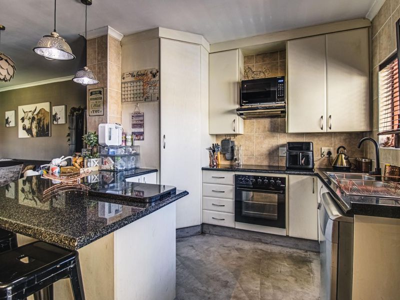Open-plan kitchen featuring granite countertops, built-in oven, hob, extractor fan, and a central island, seamlessly flowing into the adjacent living area.
