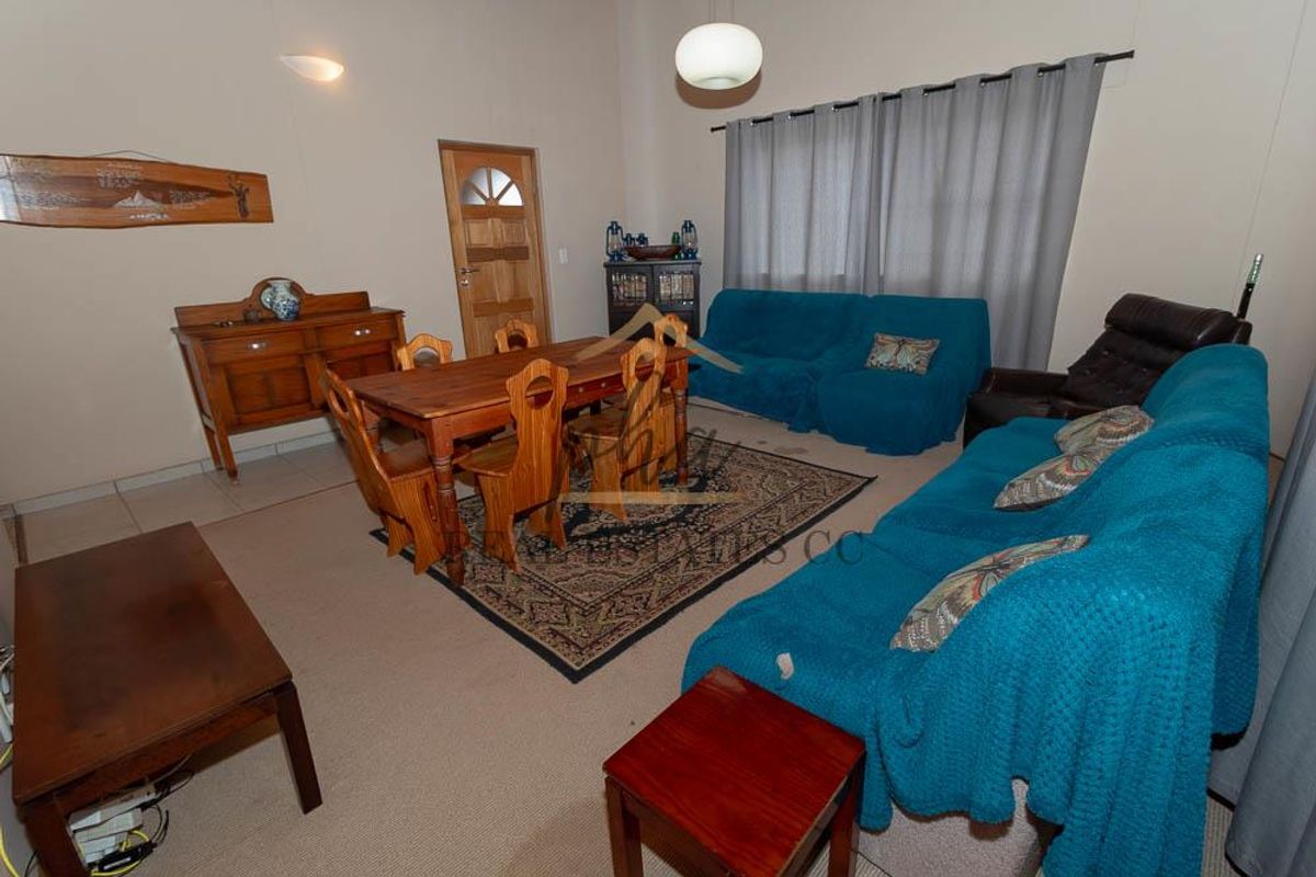 A spacious living area featuring neutral wall tones, tiled flooring, and a timber door, offering a functional layout for comfortable family living.