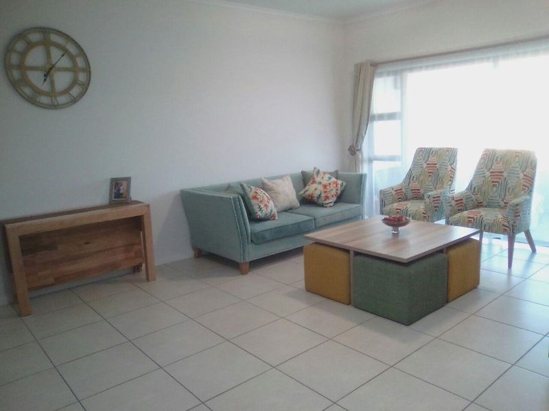 A bright living room featuring neutral tiled flooring and a large sliding glass door that provides ample natural light.