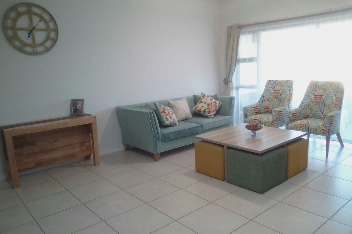 A bright living room featuring neutral tiled flooring and a large sliding glass door that provides ample natural light.