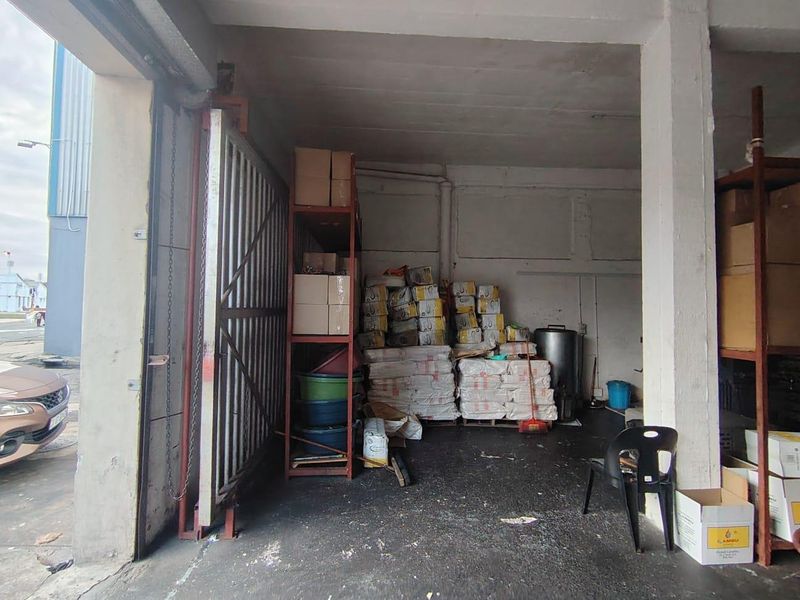 Industrial utility or storage space featuring concrete flooring, structural columns, and a large sliding access gate.