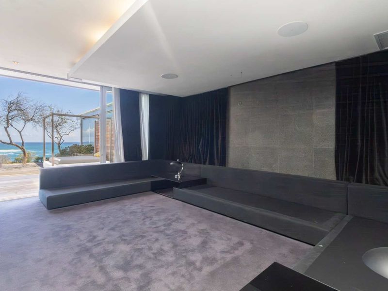 Modern living room featuring built-in seating, a stone feature wall, and large sliding glass doors opening to an ocean view deck.