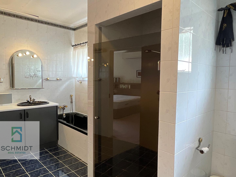 A functional bathroom featuring a built-in vanity, drop-in bathtub, and a separate glass-enclosed shower area with tiled finishes.