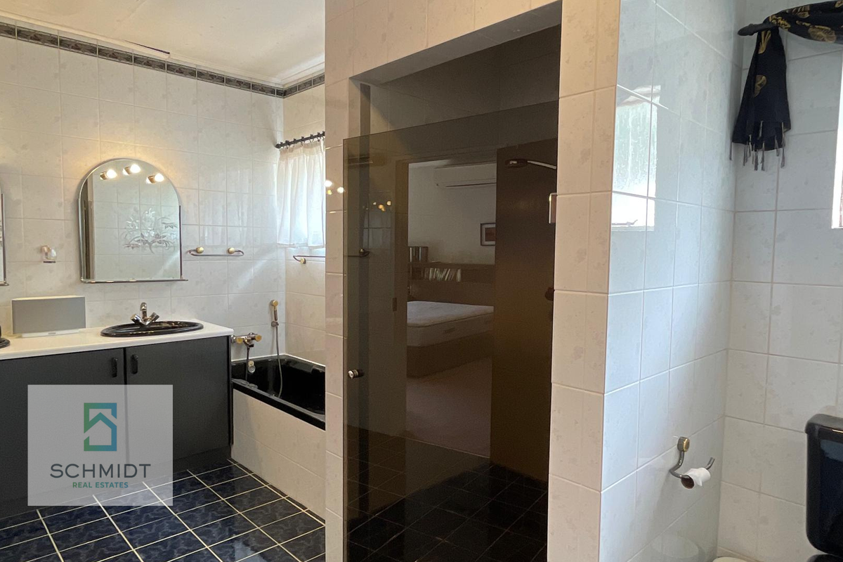 A functional bathroom featuring a built-in vanity, drop-in bathtub, and a separate glass-enclosed shower area with tiled finishes.
