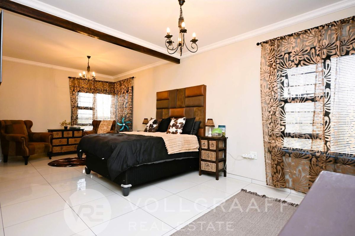 Spacious bedroom featuring tiled flooring, decorative ceiling coving, and exposed timber ceiling beams, offering a comfortable and well-maintained living space.