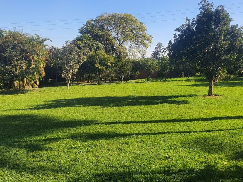 A spacious, well-maintained garden area featuring expansive green lawn and mature trees, providing a peaceful outdoor setting.