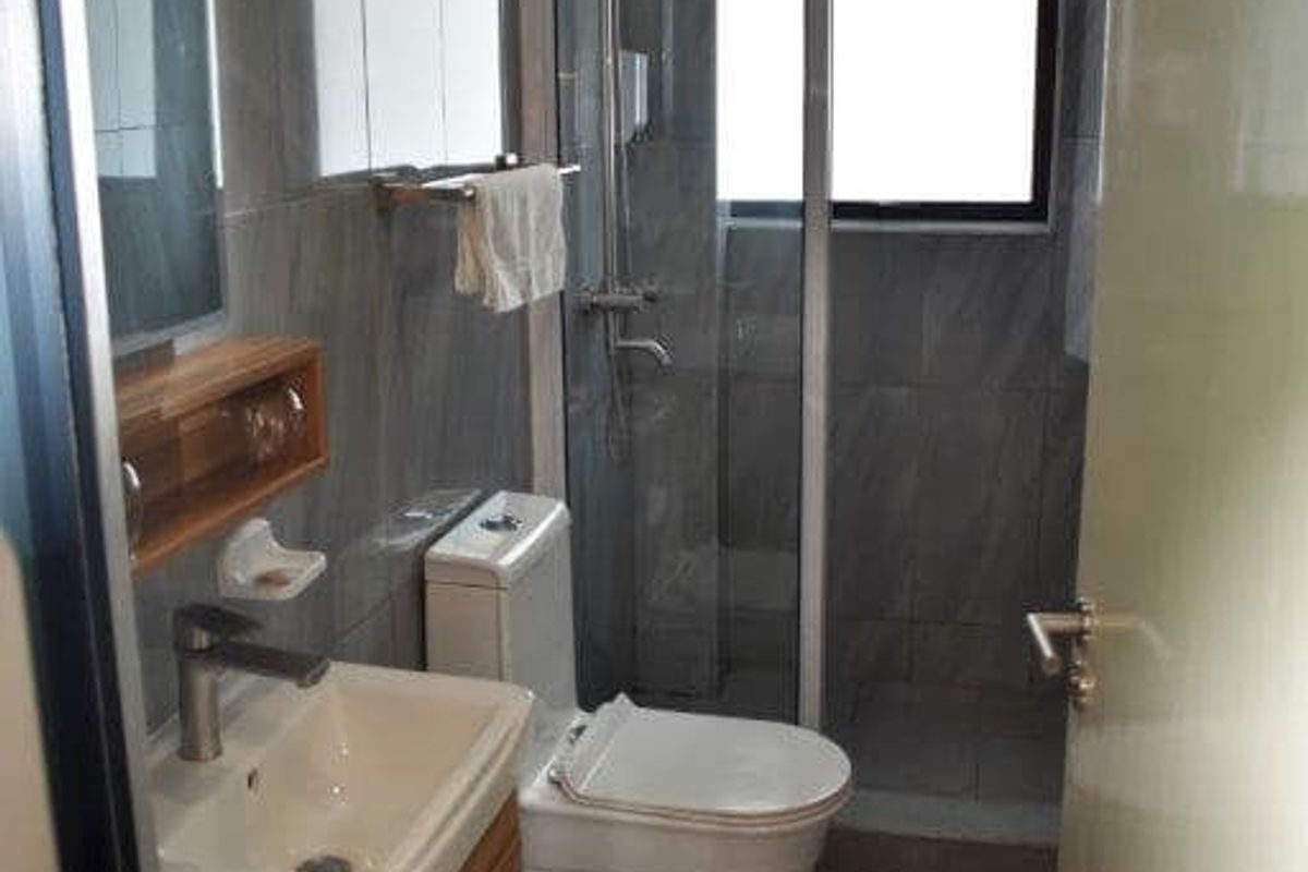 Compact bathroom featuring a modern vanity, a glass-enclosed shower, and grey wall tiling.