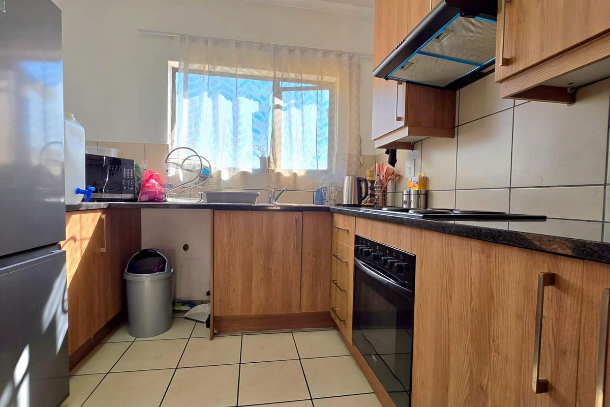 A functional kitchen featuring wood-look cabinetry, dark granite countertops, a built-in oven, and an extractor fan with tiled splashbacks.