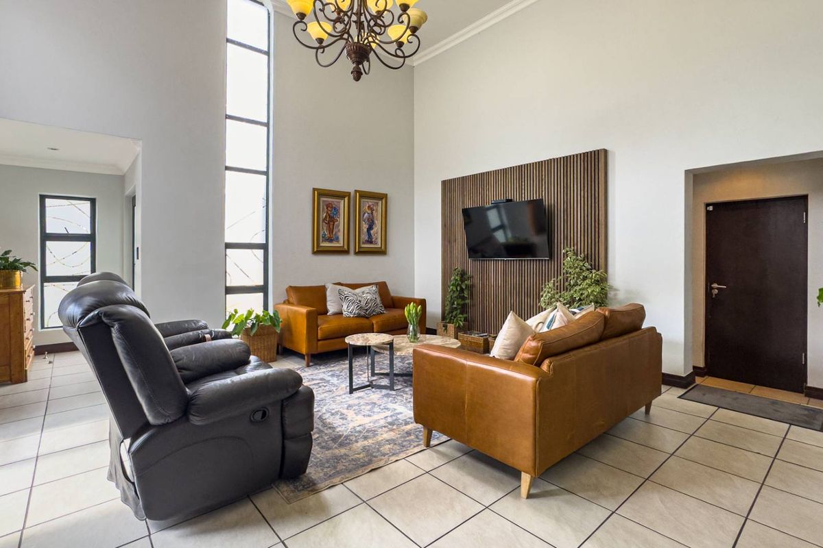 Spacious living room featuring high ceilings, a vertical feature window, and a modern timber-slat wall panel for media mounting.