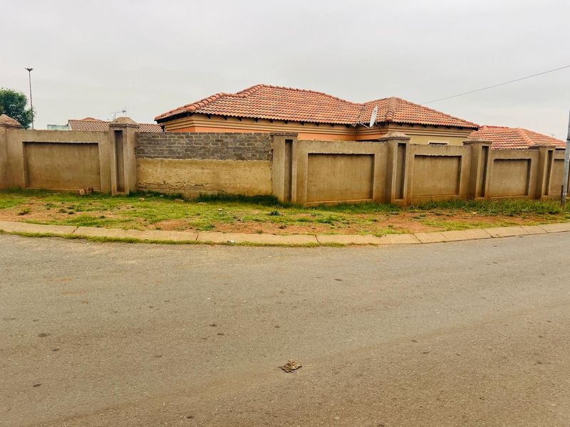 Street view of the property showing the perimeter wall and tiled roof structure from the road.