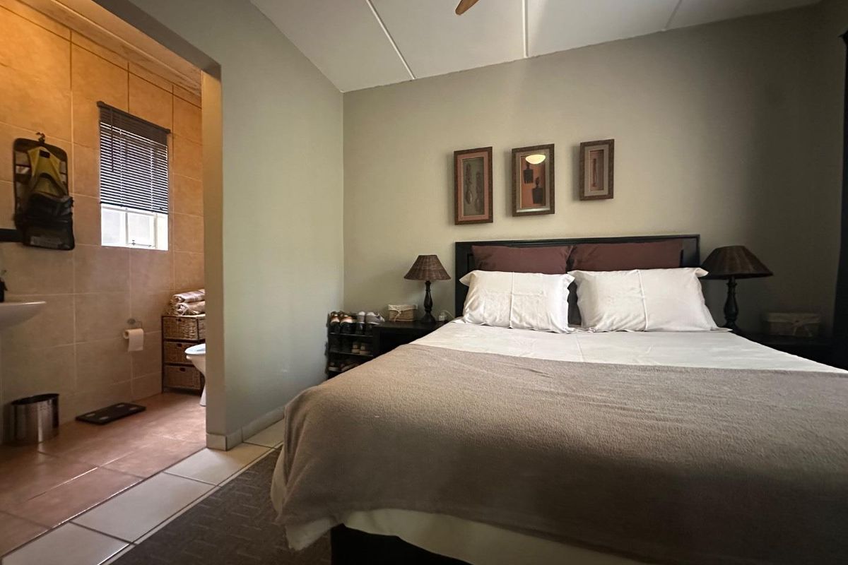A bedroom featuring an en-suite bathroom with tiled walls and flooring, providing a functional and connected living space.