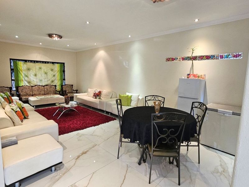 Spacious open-plan living and dining area featuring polished marble-look floor tiles and recessed downlighting throughout.