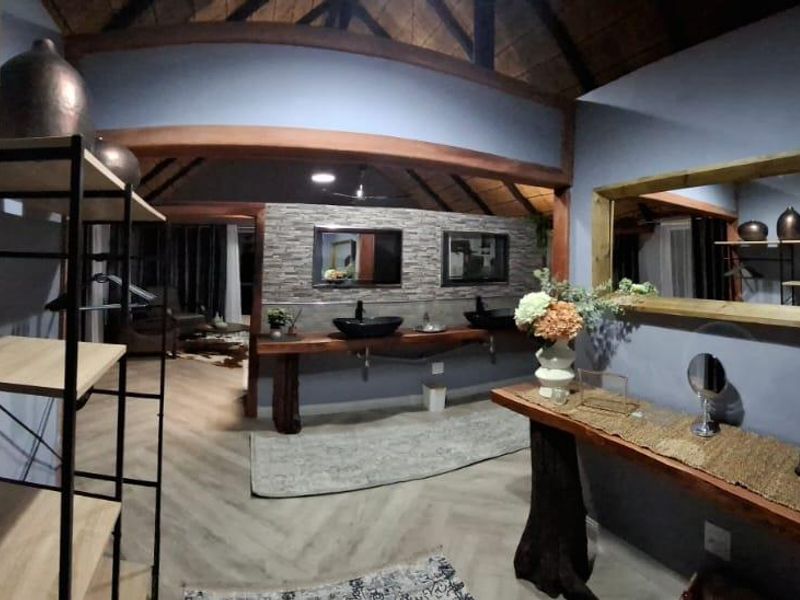 Spacious bathroom featuring a double vanity with vessel sinks, stone cladding, and exposed timber roof trusses in a lodge-style setting.