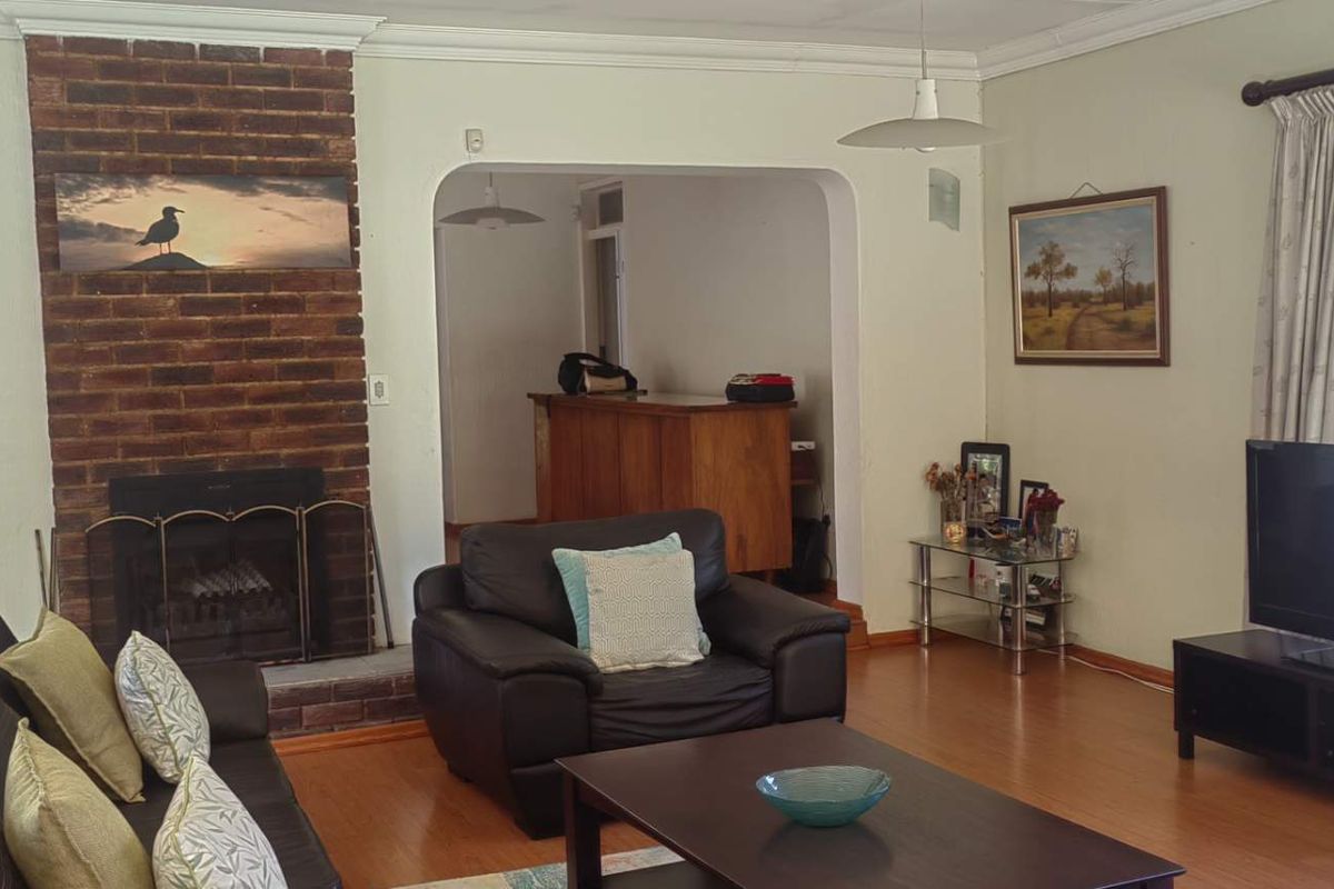 A living room featuring a brick fireplace, laminate flooring, and an arched entryway leading to an adjacent space.