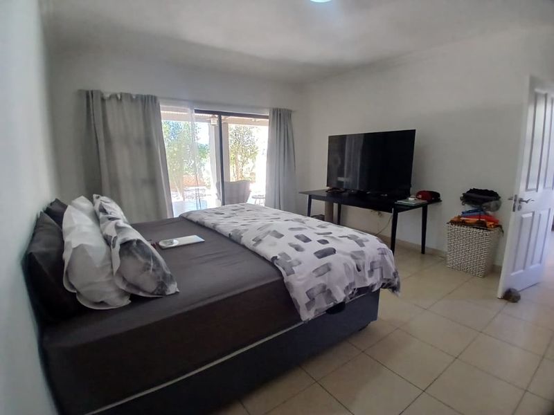 A bedroom featuring tiled flooring and a sliding glass door providing access to the outdoor area.