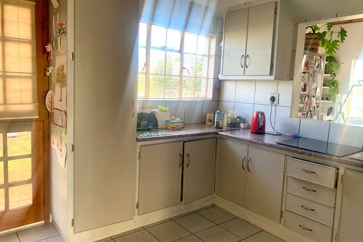 A functional kitchen featuring built-in cabinetry, tiled flooring, and a window providing natural light, with direct access to an exterior door.