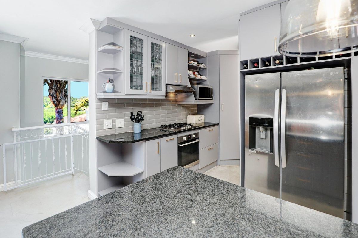 Modern kitchen featuring grey cabinetry, granite countertops, subway tile backsplash, built-in oven, gas hob, extractor fan, and integrated wine rack.