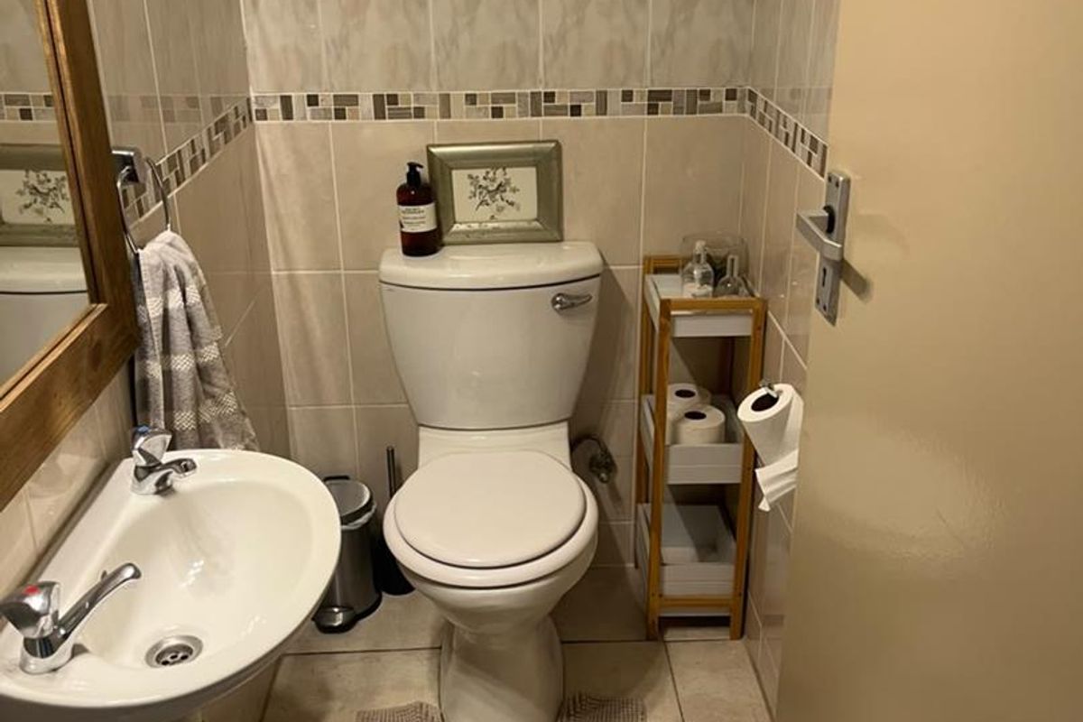 A compact guest bathroom featuring neutral ceramic wall and floor tiles, a pedestal basin, and a standard close-coupled toilet.