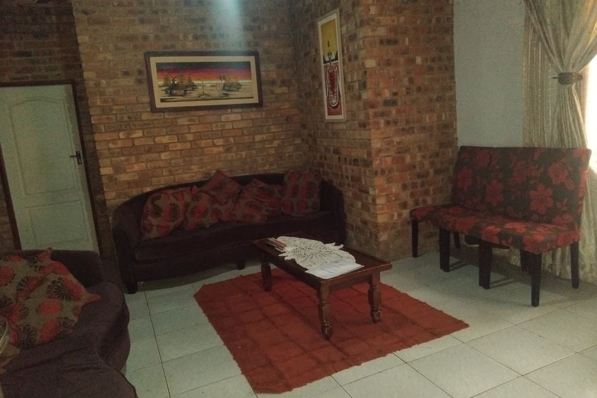 A living room featuring exposed brick walls and tiled flooring, offering a rustic aesthetic with potential for modern updates.