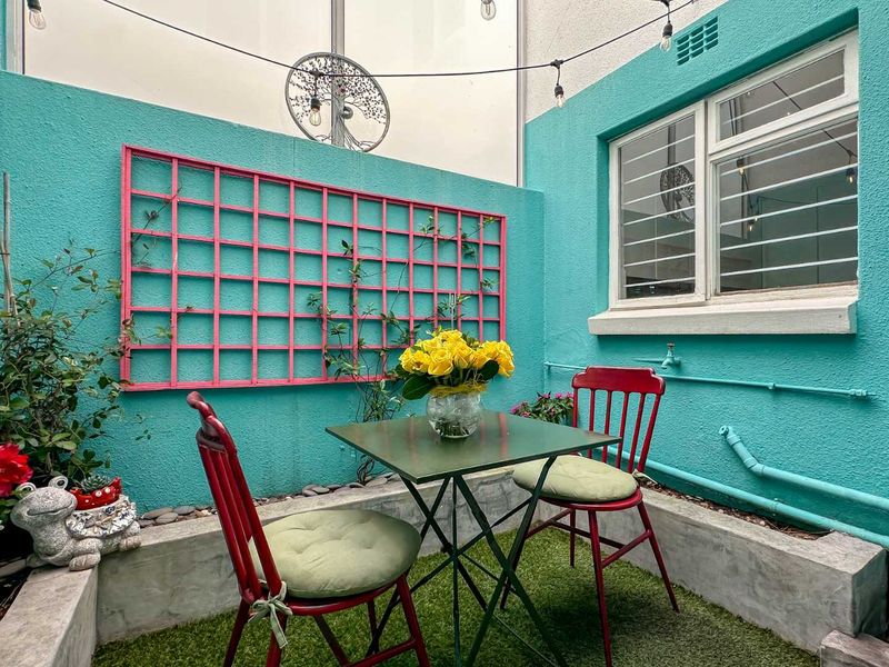 A compact, enclosed patio area featuring a concrete planter box, security-barred window, and decorative wall trellis.