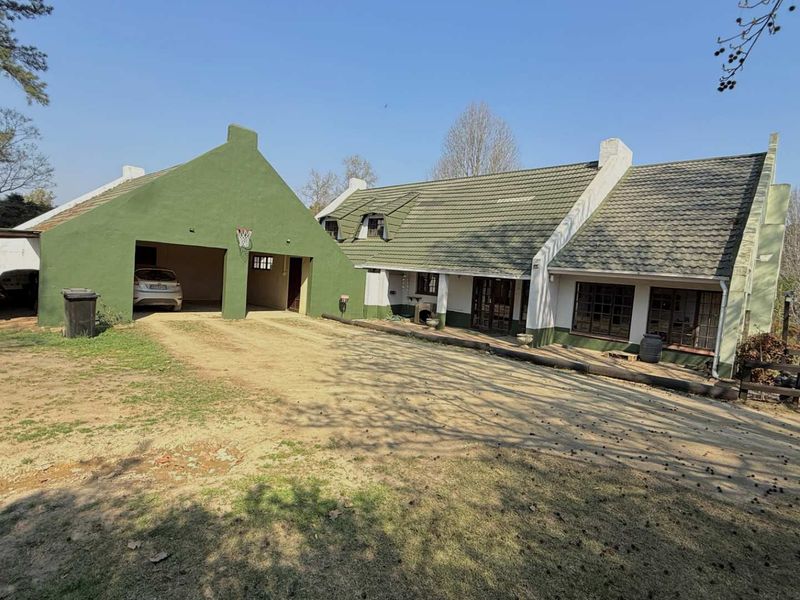Front exterior view of a farm-style residence featuring a double garage, gabled roof architecture, and a covered patio area.
