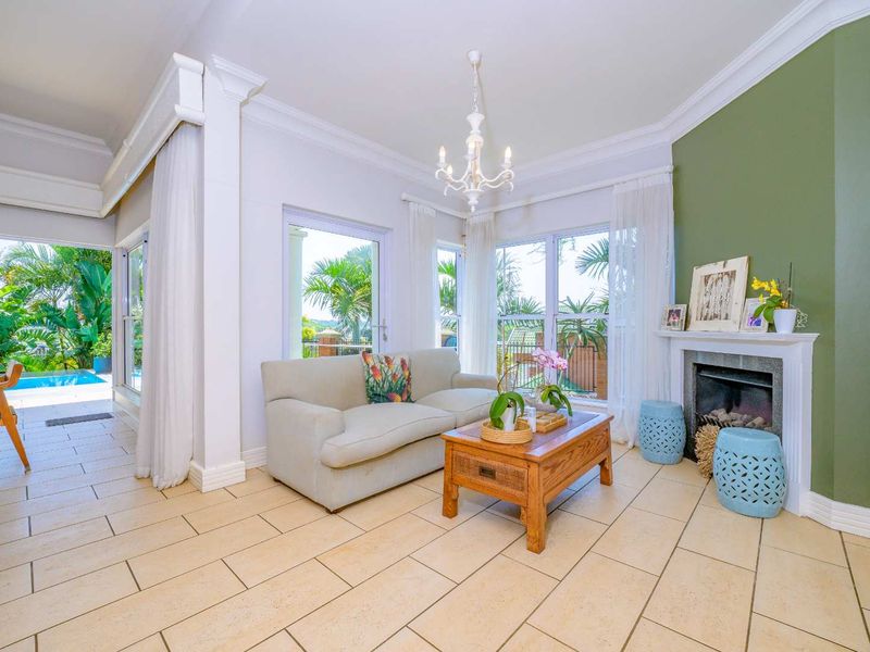 Bright living room featuring tiled flooring, a fireplace with a mantel, crown molding, and large sliding glass doors opening to a pool area.