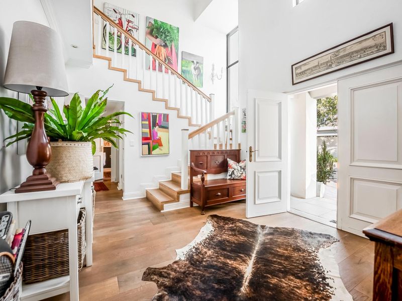 Bright and welcoming entrance hall featuring a timber staircase, high ceilings, and elegant wooden flooring leading into the main living areas.