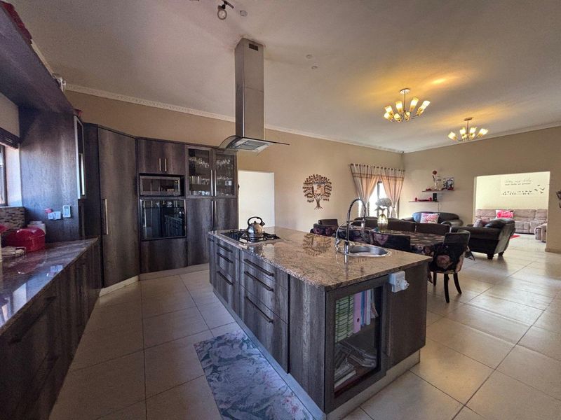Spacious open-plan kitchen and living area featuring a large central island with granite countertops, modern cabinetry, and integrated appliances.