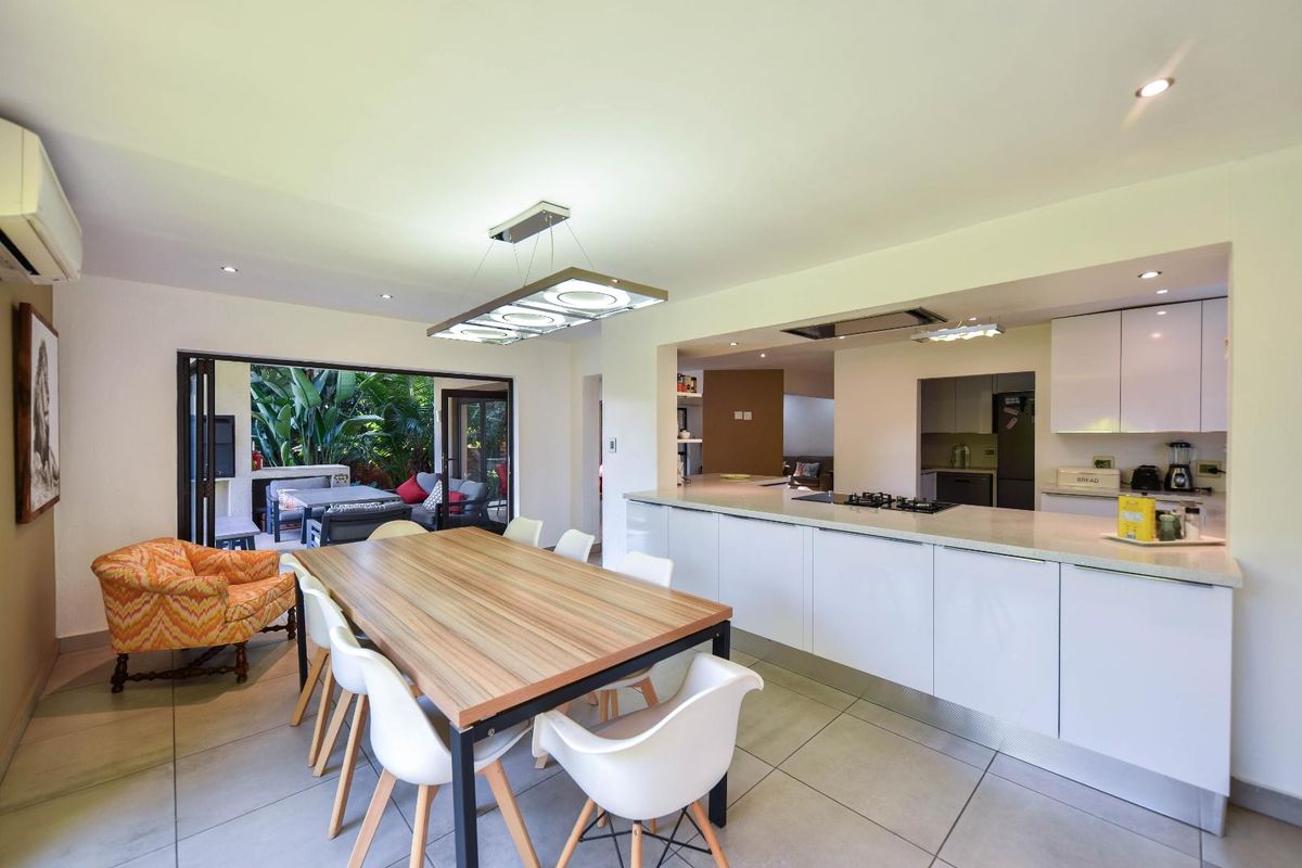 Spacious open-plan kitchen and dining area featuring modern cabinetry, a central island with gas hob, and seamless access to the outdoor patio through stacking doors.