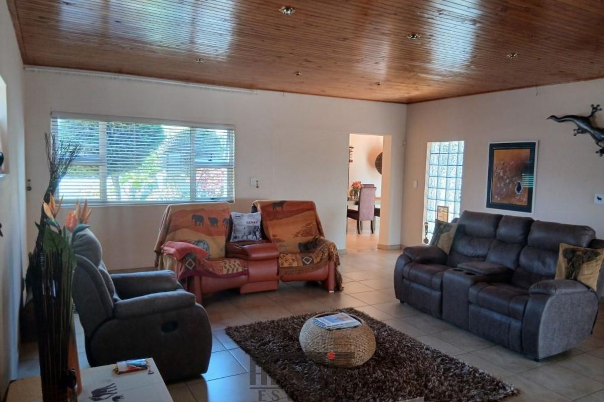 Spacious living room featuring a timber-clad ceiling, tiled flooring, and a glass block feature wall, providing a warm and inviting atmosphere.