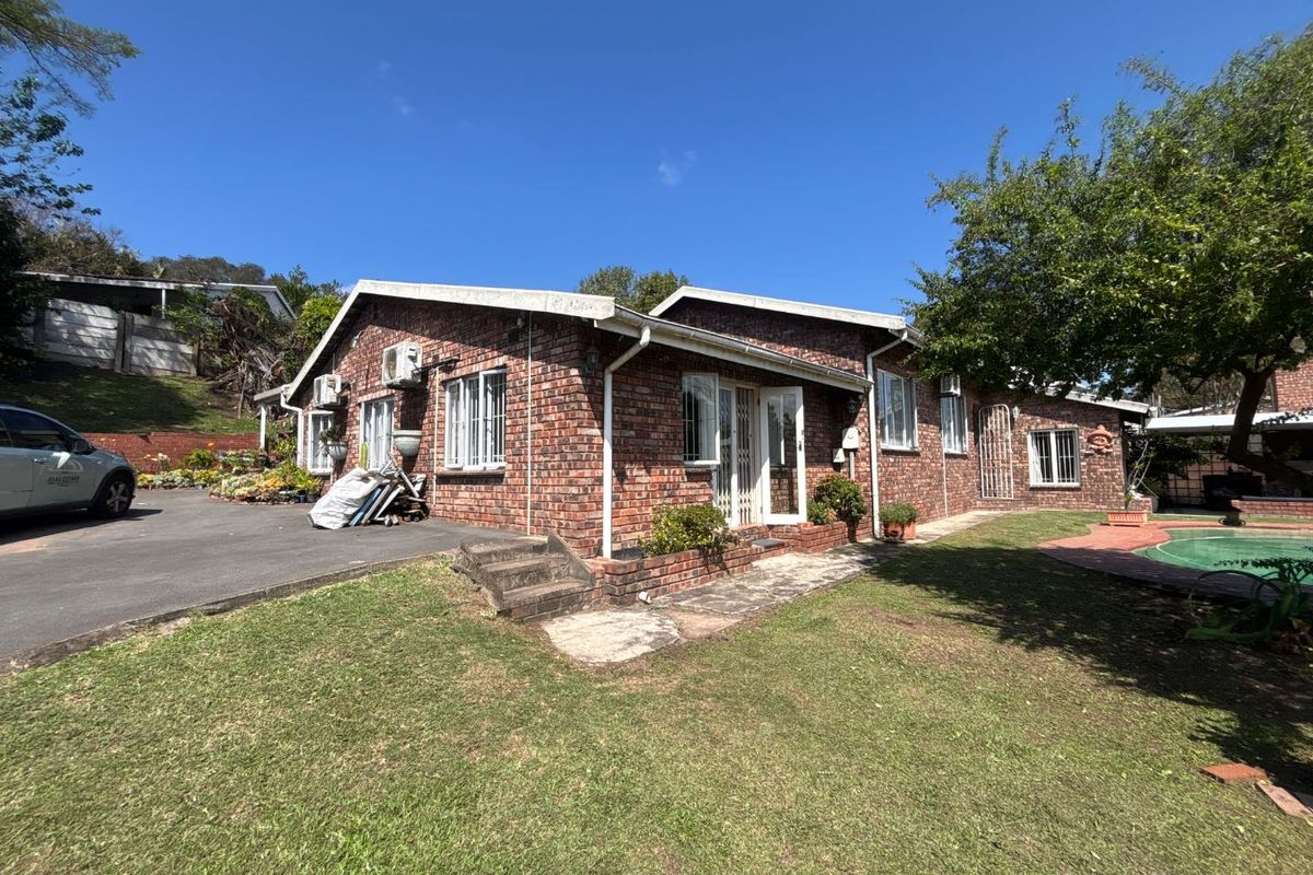 Rear view of a face brick house featuring a paved walkway, driveway, and access to a swimming pool area.