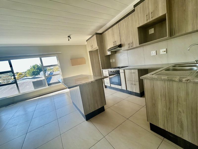 Modern kitchen featuring wood-look cabinetry, granite countertops, a central island, and built-in appliances, offering a clean and functional workspace.