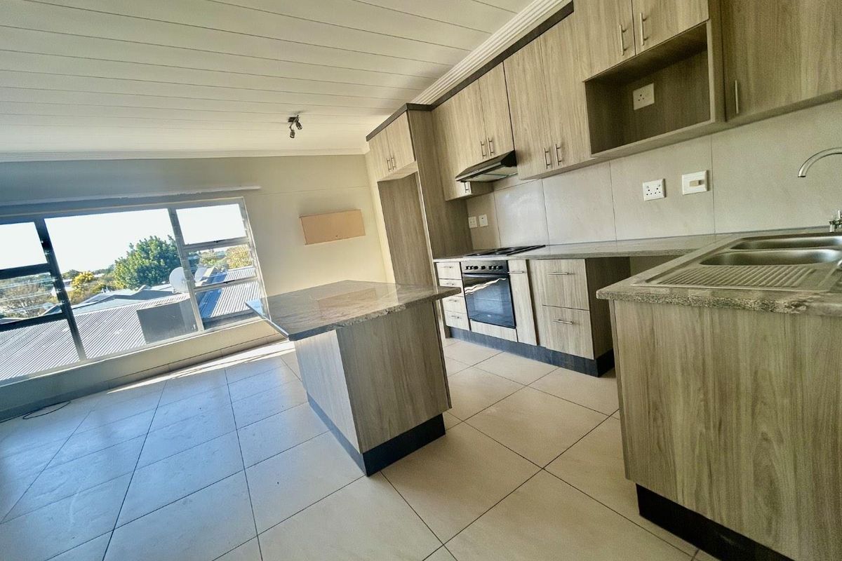 Modern kitchen featuring wood-look cabinetry, granite countertops, a central island, and built-in appliances, offering a clean and functional workspace.