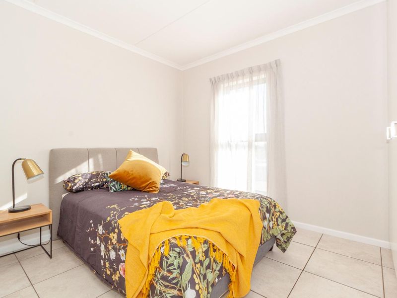 A bright and well-maintained bedroom featuring neutral tiled flooring, built-in cupboards, and clean finishes, offering a comfortable and functional living space.