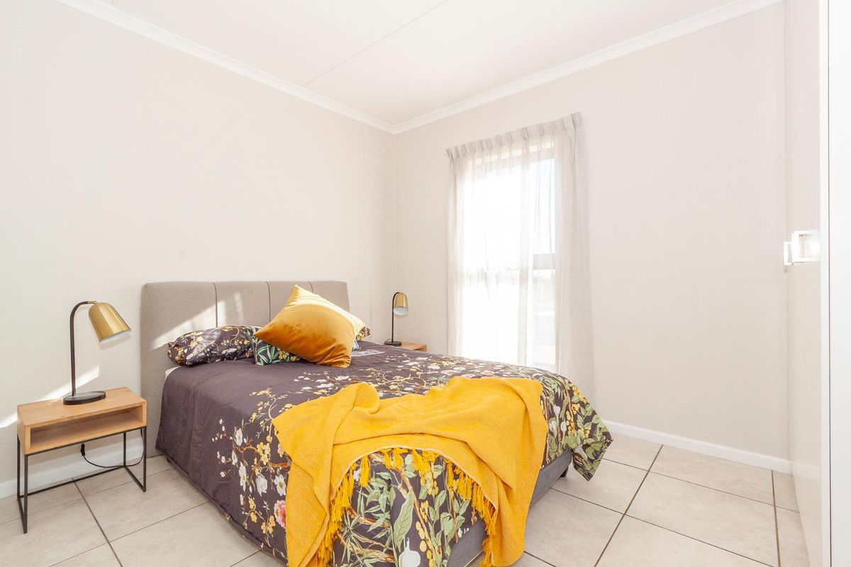 A bright and well-maintained bedroom featuring neutral tiled flooring, built-in cupboards, and clean finishes, offering a comfortable and functional living space.