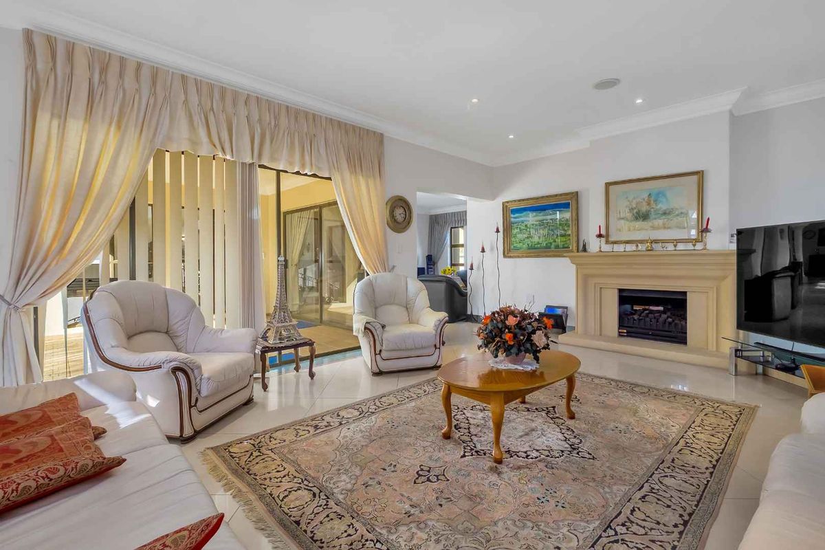 Spacious living room featuring a built-in stone fireplace, tiled flooring, recessed downlighting, and large sliding glass doors leading to an outdoor patio area.
