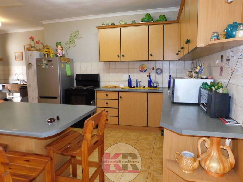 A functional kitchen featuring laminate cabinetry, tiled backsplash, and a breakfast bar, offering a practical layout for daily meal preparation.