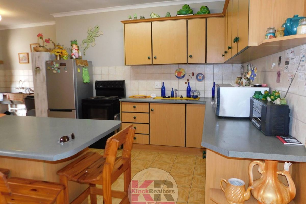 A functional kitchen featuring laminate cabinetry, tiled backsplash, and a breakfast bar, offering a practical layout for daily meal preparation.