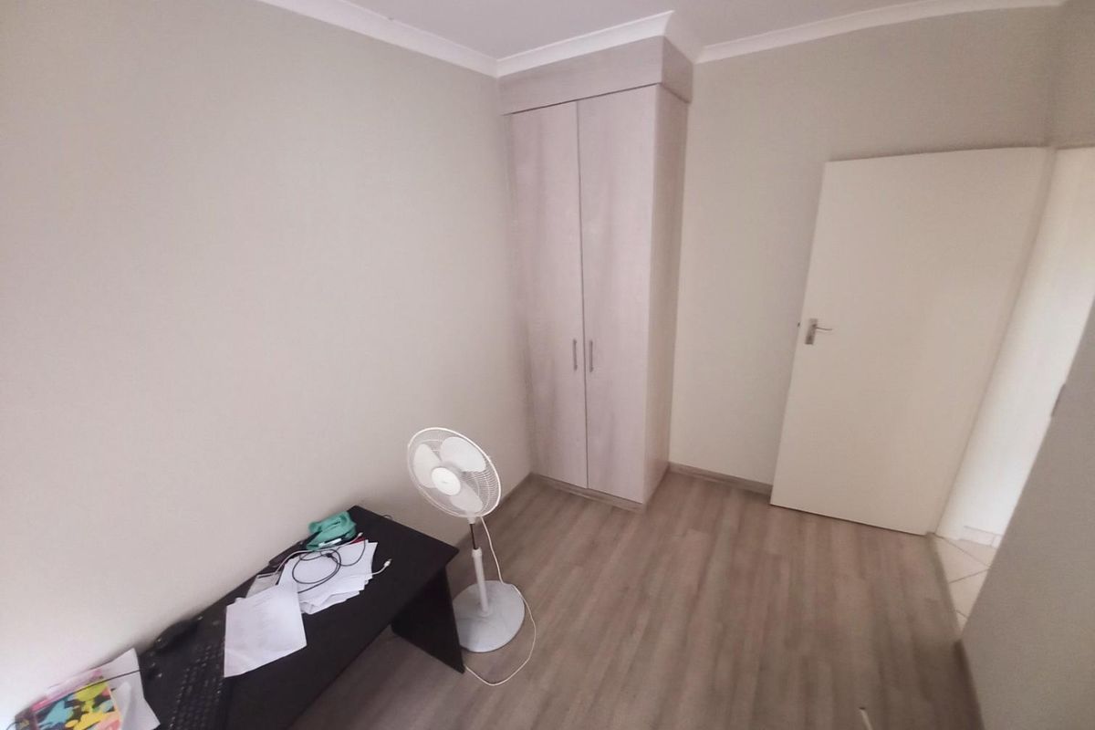 A bedroom featuring light wood-look laminate flooring, neutral wall paint, and a built-in wardrobe with light wood-grain finish.