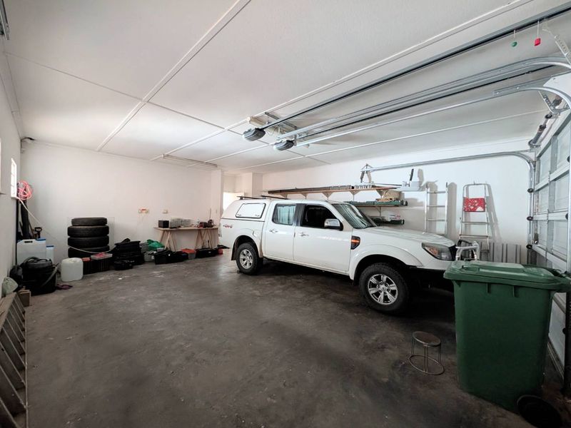 Spacious double garage featuring concrete flooring, automated door mechanisms, and functional overhead storage shelving.