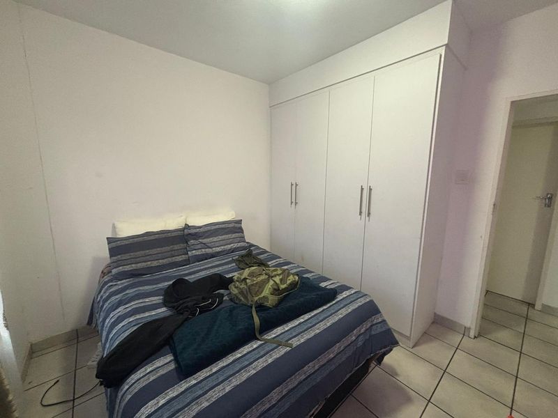 A bedroom featuring built-in white cupboards and tiled flooring, providing functional storage space.